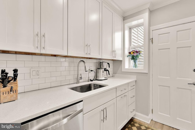 kitchen featuring backsplash, a sink, light countertops, white cabinetry, and stainless steel dishwasher