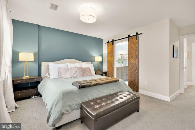 bedroom with visible vents, a barn door, carpet flooring, ensuite bath, and baseboards