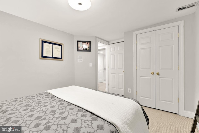 bedroom featuring a closet, visible vents, and light carpet