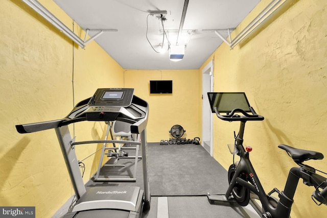 workout room featuring a garage and a textured wall