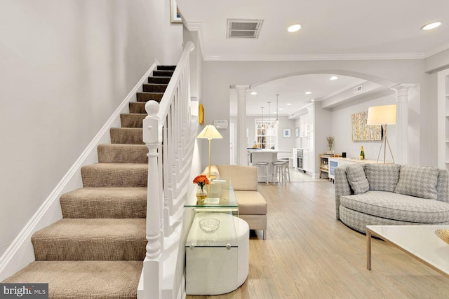 stairs featuring arched walkways, wood finished floors, visible vents, and ornate columns