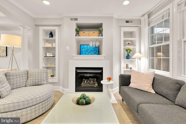 living room with crown molding, wood finished floors, visible vents, and built in features