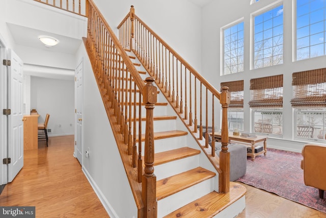 stairs with wood-type flooring and a towering ceiling