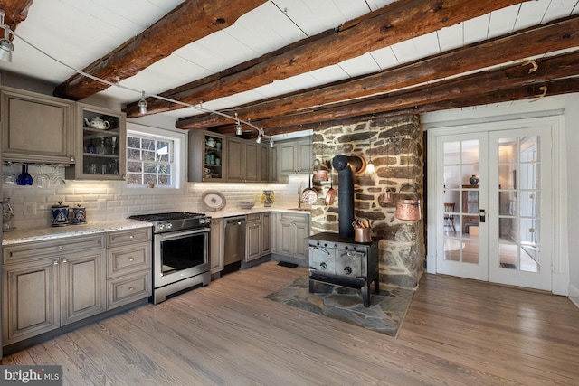 kitchen featuring appliances with stainless steel finishes, beamed ceiling, decorative backsplash, dark wood-type flooring, and french doors