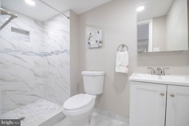 bathroom featuring vanity, a tile shower, and toilet