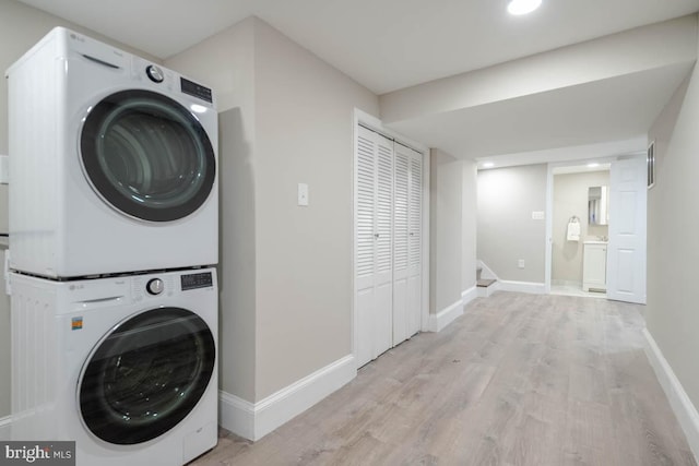 washroom featuring stacked washer / drying machine and light hardwood / wood-style floors