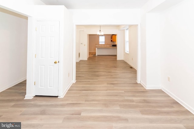 corridor featuring an inviting chandelier and light hardwood / wood-style floors