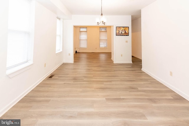 unfurnished dining area featuring a notable chandelier and light hardwood / wood-style flooring