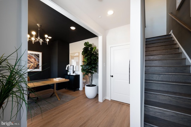 stairway featuring wood-type flooring and an inviting chandelier