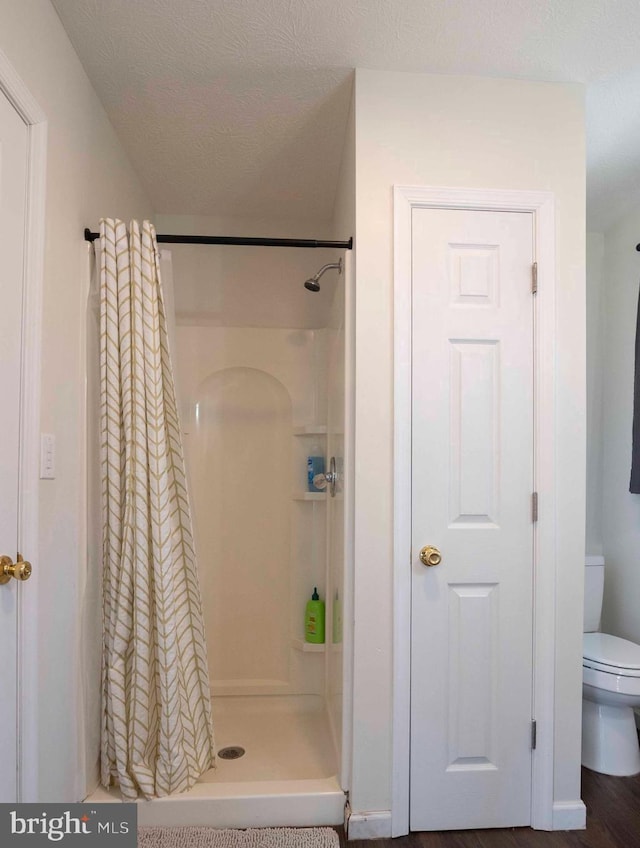 full bath featuring a shower stall, toilet, and a textured ceiling