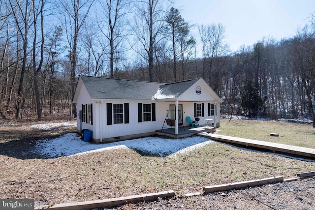 view of front facade featuring a forest view, a shingled roof, and crawl space