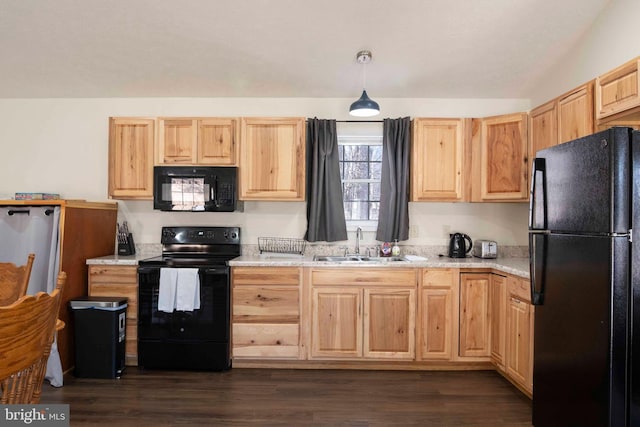 kitchen with a sink, light brown cabinetry, light stone countertops, black appliances, and pendant lighting