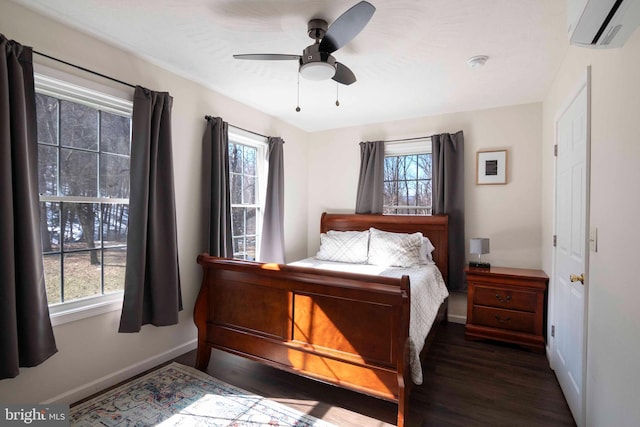 bedroom featuring dark wood-style flooring, multiple windows, a wall mounted air conditioner, and baseboards