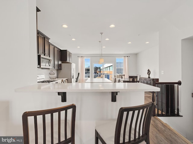 kitchen featuring decorative light fixtures, kitchen peninsula, stainless steel appliances, and a breakfast bar area