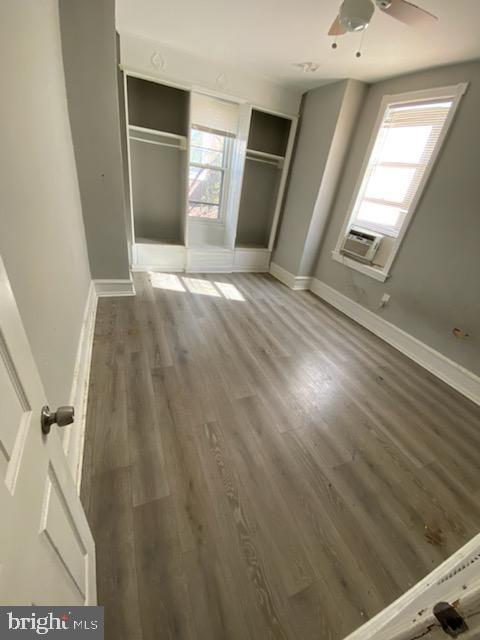 unfurnished bedroom featuring cooling unit, dark hardwood / wood-style flooring, and a closet