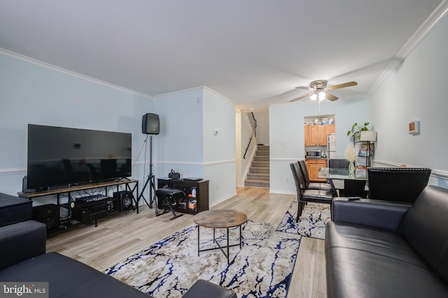 living room with crown molding, ceiling fan, and light wood-type flooring