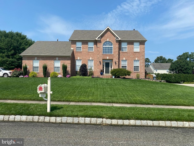 colonial home featuring a front lawn, brick siding, and a shingled roof