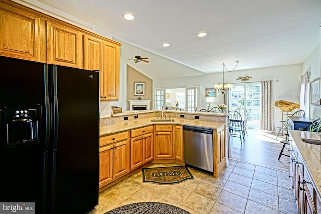 kitchen with a fireplace, a sink, stainless steel dishwasher, ceiling fan with notable chandelier, and black refrigerator with ice dispenser