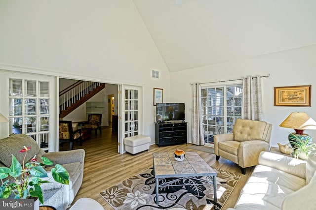 living room featuring stairs, wood finished floors, visible vents, and high vaulted ceiling