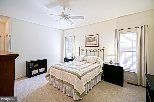 bedroom featuring visible vents, baseboards, light colored carpet, and a ceiling fan