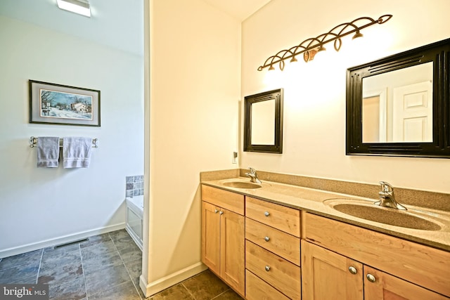 full bathroom with double vanity, a bathtub, baseboards, and a sink