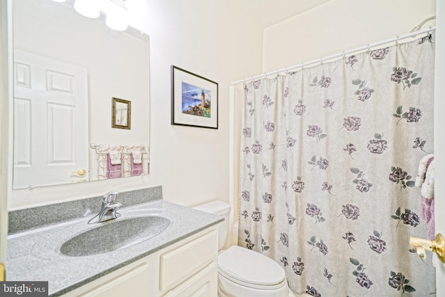 full bathroom featuring a shower with shower curtain, toilet, and vanity