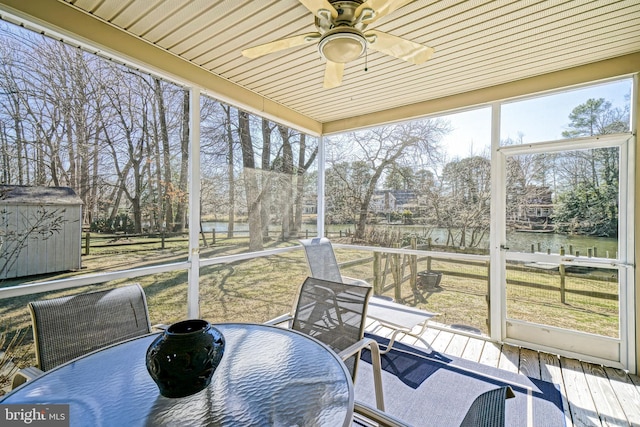 sunroom / solarium with a water view and ceiling fan