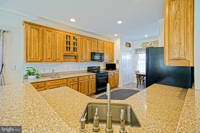 kitchen featuring brown cabinetry, black appliances, and a sink