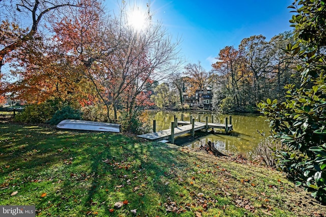 view of dock with a yard and a water view