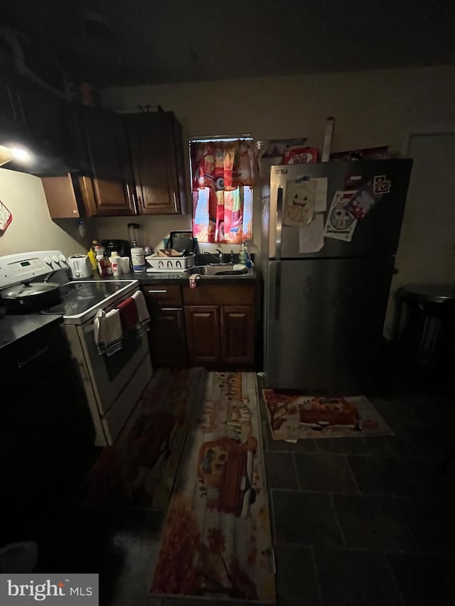 kitchen featuring dark brown cabinetry, sink, stainless steel fridge, and white electric range oven