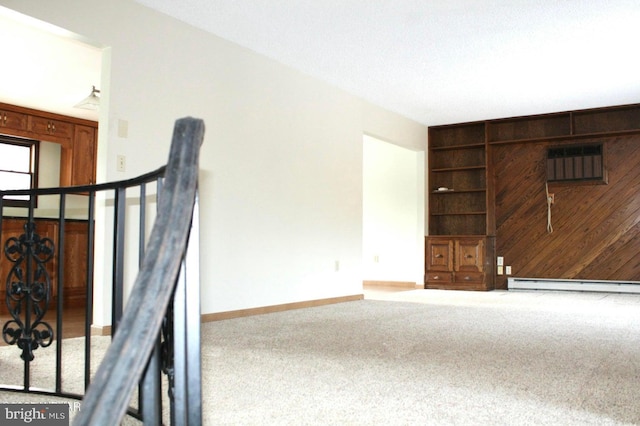 unfurnished living room with built in shelves, wooden walls, baseboard heating, and carpet