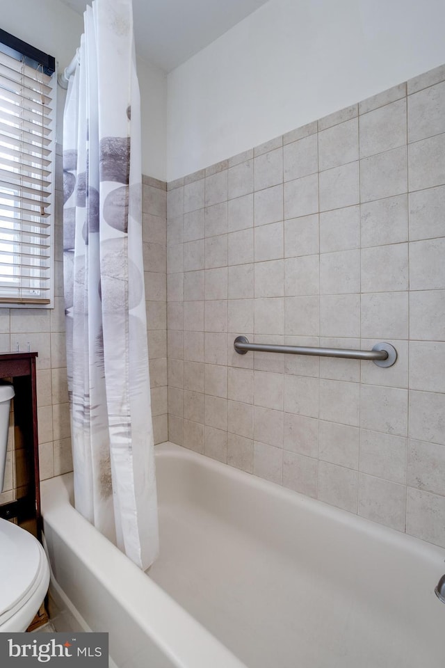 bathroom with shower / bath combination with curtain and toilet