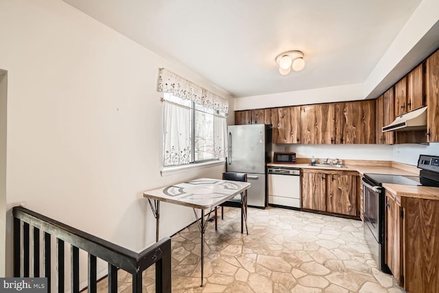 kitchen featuring stone finish floor, stainless steel appliances, light countertops, under cabinet range hood, and a sink