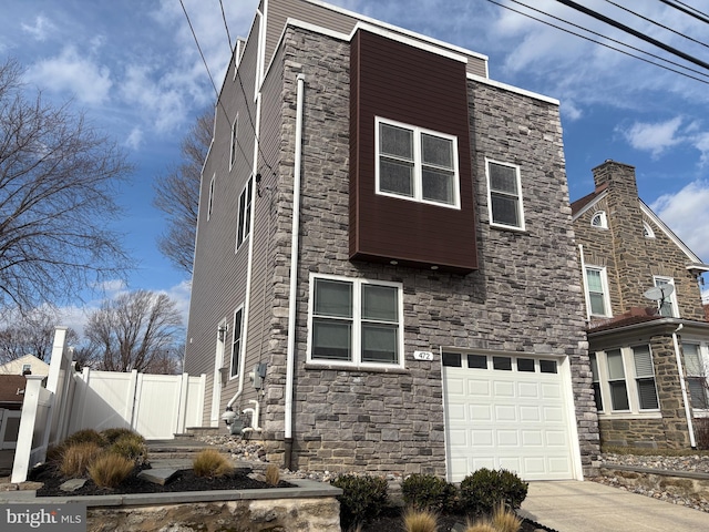 view of front facade featuring an attached garage, driveway, and fence