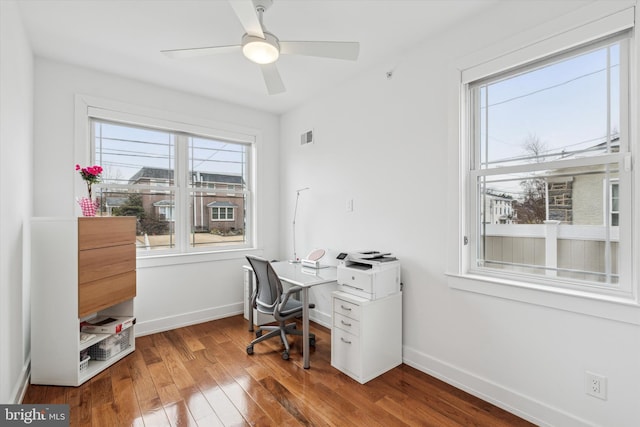 office featuring hardwood / wood-style floors, a ceiling fan, visible vents, and baseboards