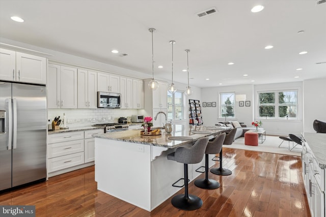 kitchen with dark wood finished floors, stainless steel appliances, tasteful backsplash, visible vents, and open floor plan