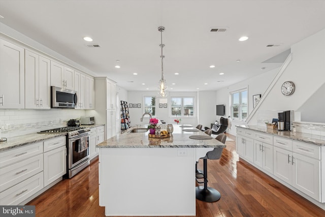 kitchen featuring appliances with stainless steel finishes, dark wood finished floors, visible vents, and a sink