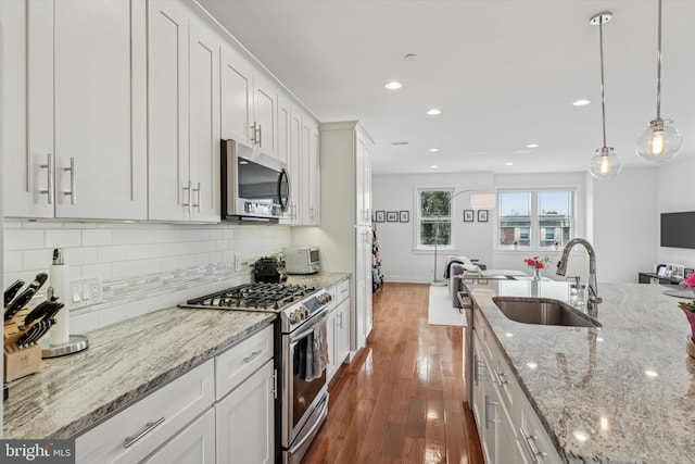 kitchen with backsplash, appliances with stainless steel finishes, open floor plan, and a sink