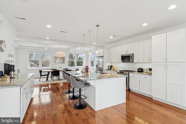 kitchen with white cabinets, visible vents, stainless steel appliances, and hardwood / wood-style floors