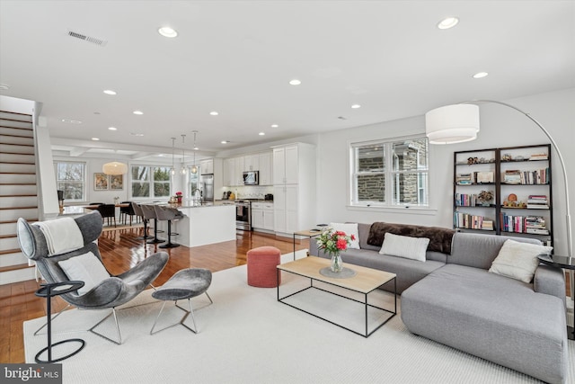 living area featuring stairs, wood finished floors, visible vents, and recessed lighting