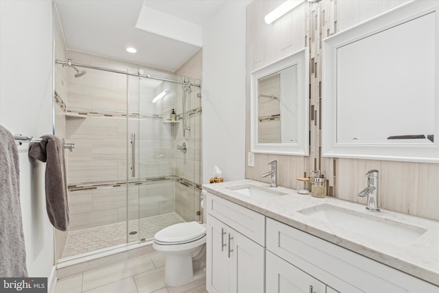 bathroom featuring toilet, a stall shower, double vanity, and a sink