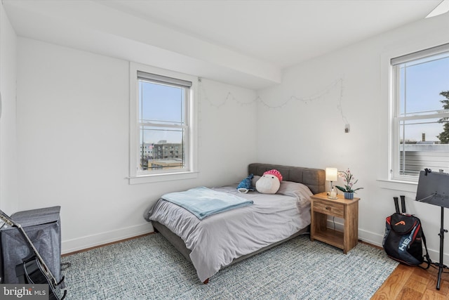 bedroom with multiple windows, baseboards, and wood finished floors