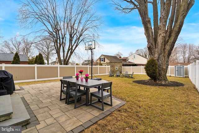 view of yard featuring a fenced backyard, an outbuilding, a patio area, a shed, and outdoor dining space