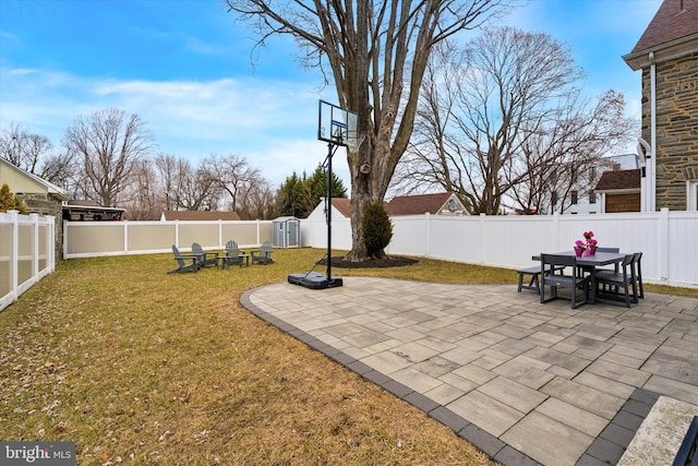 view of patio featuring outdoor dining area, a fenced backyard, an outdoor structure, and a fire pit