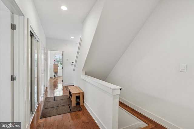 hall with recessed lighting, wood-type flooring, baseboards, and an upstairs landing