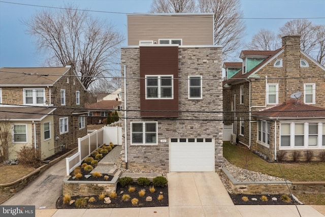 view of front of home with stone siding, concrete driveway, fence, and a garage