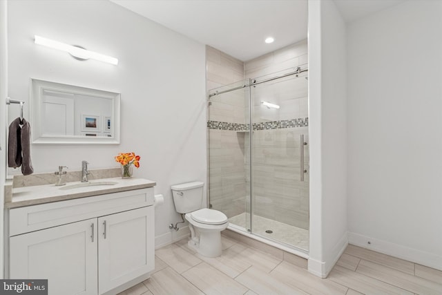 bathroom with baseboards, a shower stall, toilet, and vanity