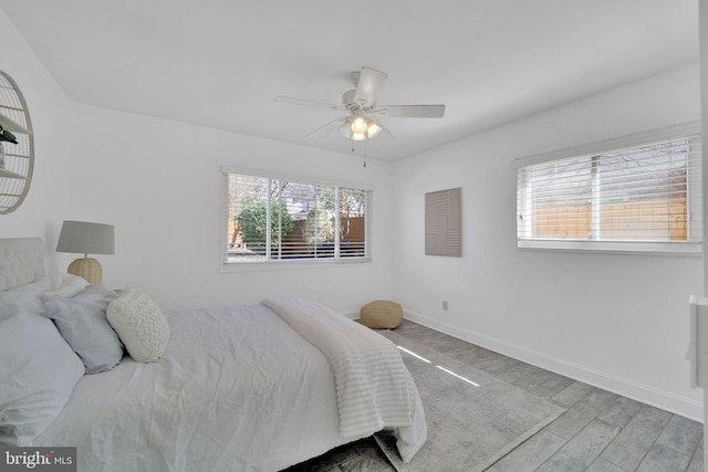 bedroom with a ceiling fan, baseboards, and wood finished floors