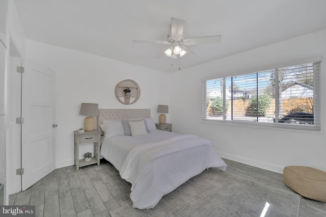 bedroom featuring a ceiling fan, baseboards, and wood finished floors