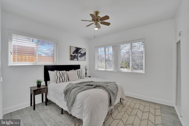 bedroom with light wood finished floors, a ceiling fan, and baseboards